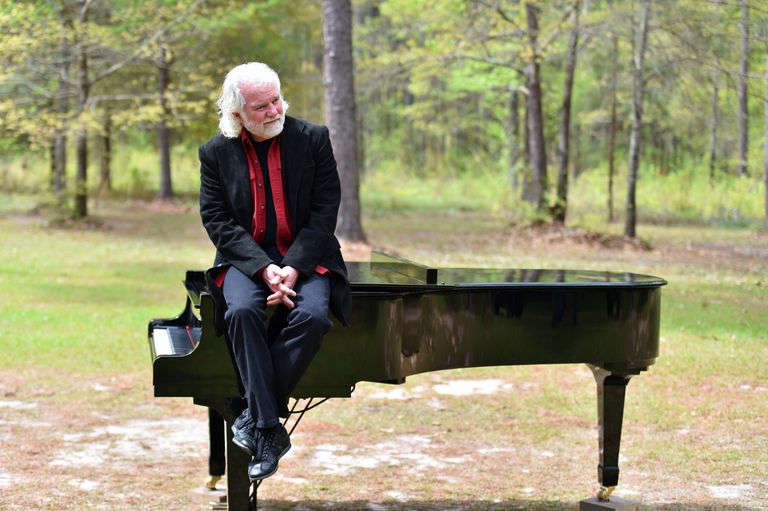 查克leavell坐钢琴在森林。